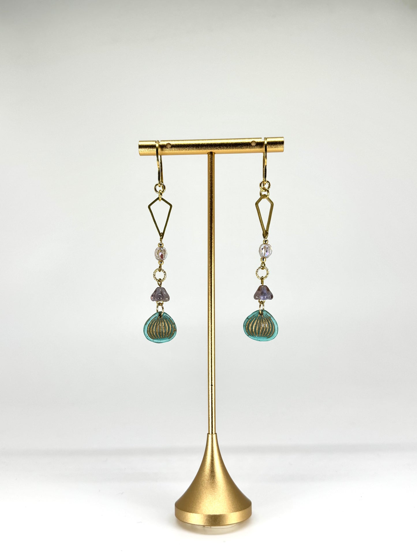 Pair of earrings on a gold stand against a white background