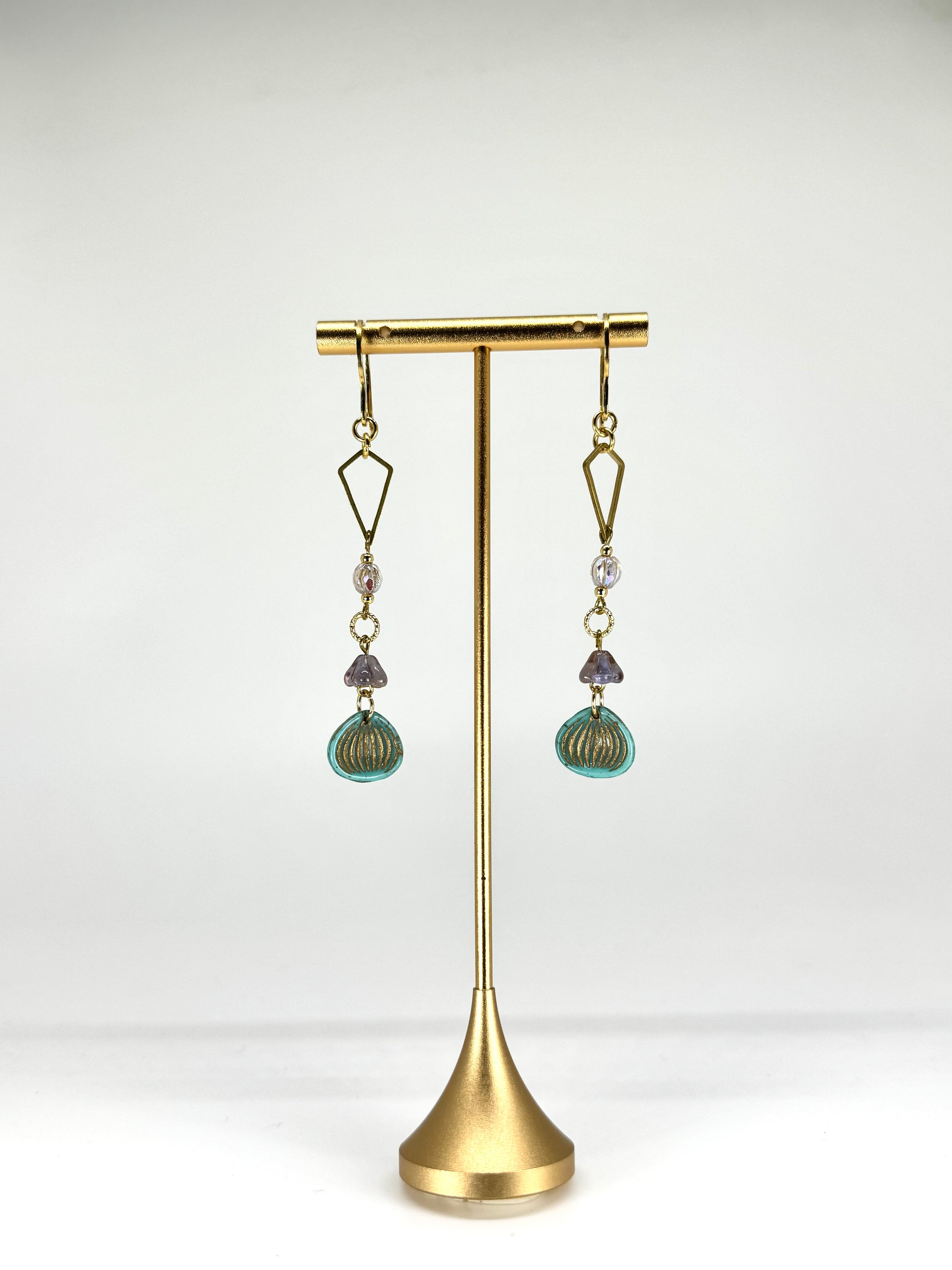 Pair of earrings on a gold stand against a white background