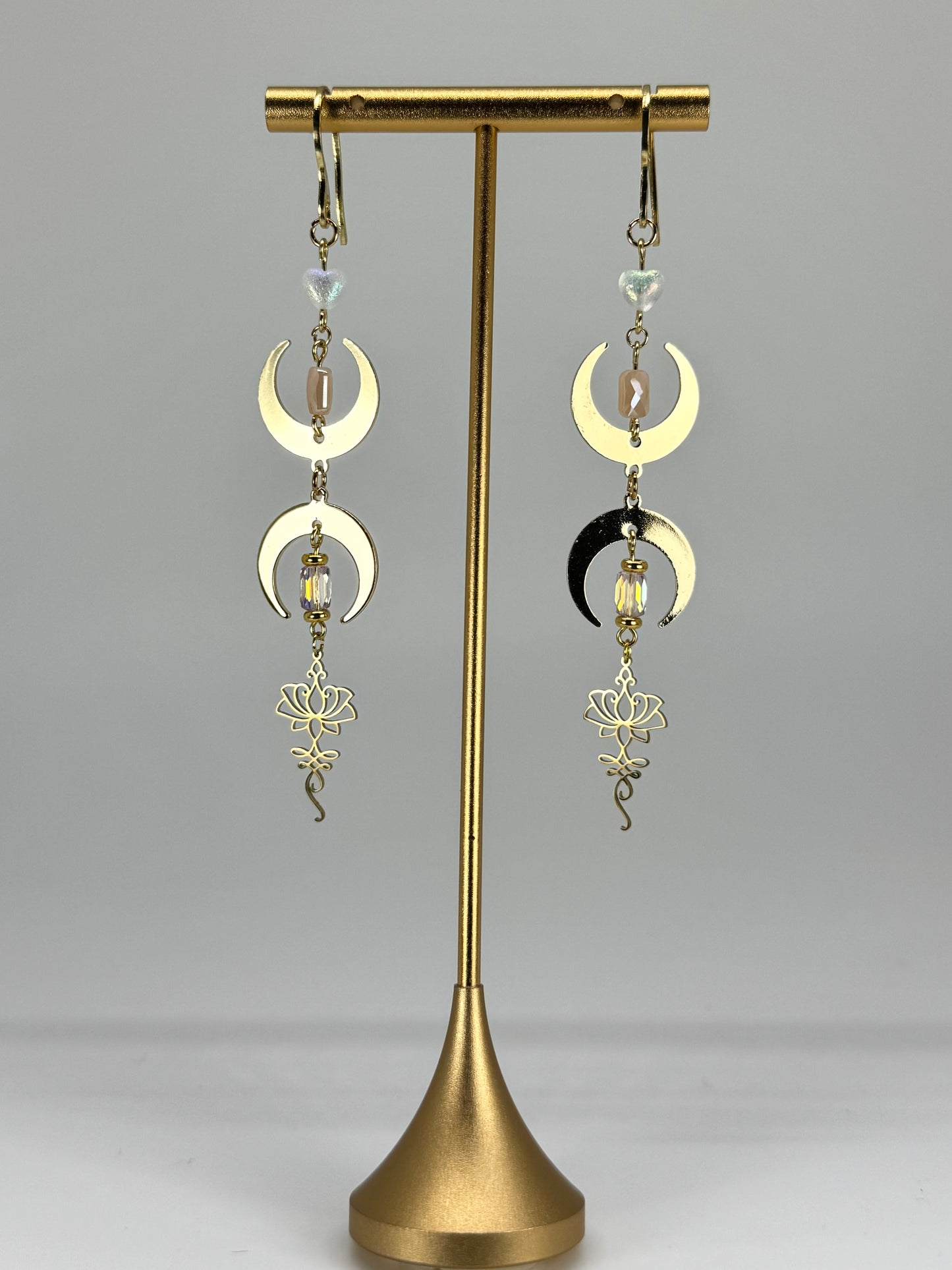 Pair of moon phase earrings on a gold stand against a white background
