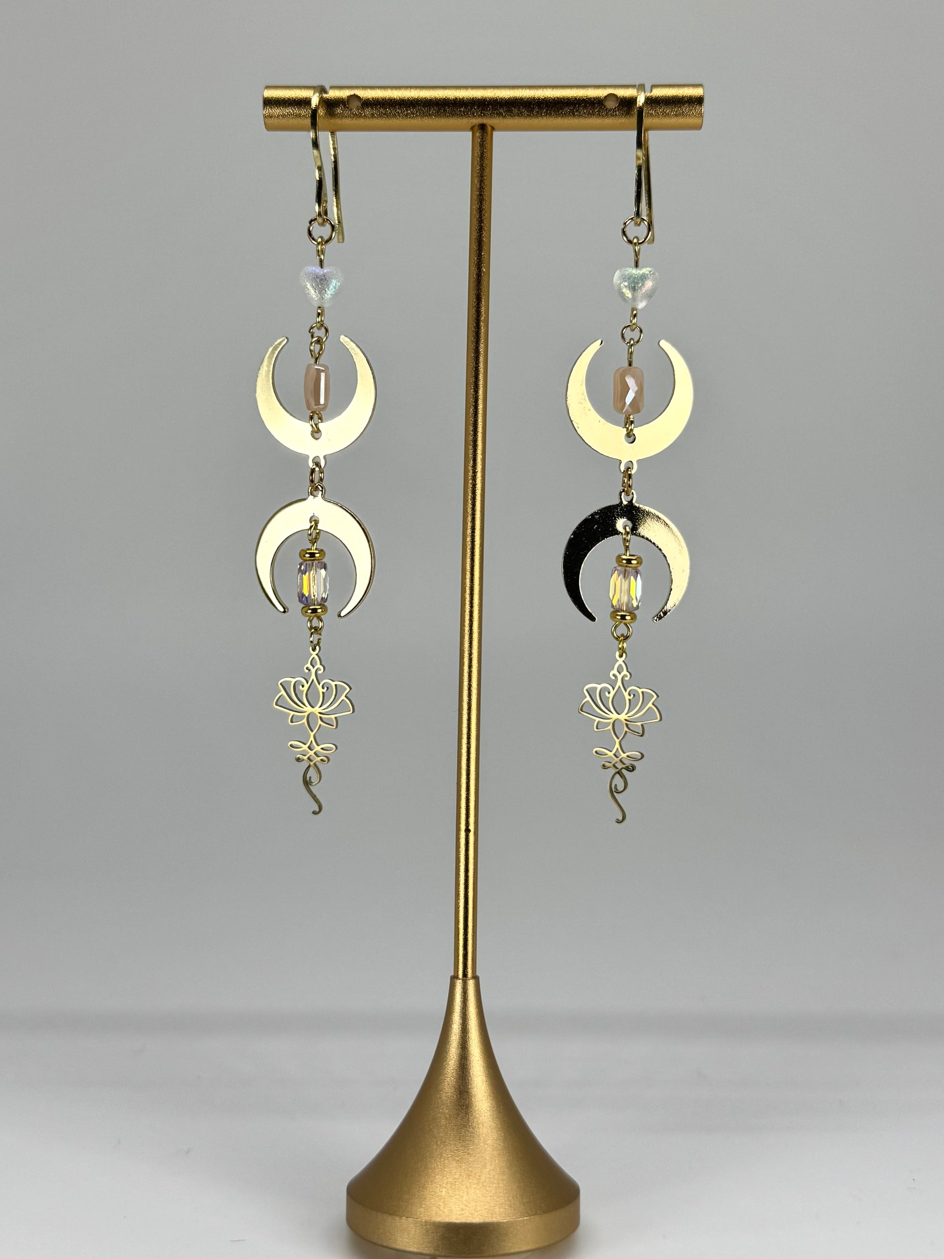 Pair of moon phase earrings on a gold stand against a white background