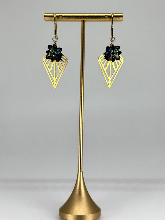 Gold earring stand with two black gemstone earrings on a white background