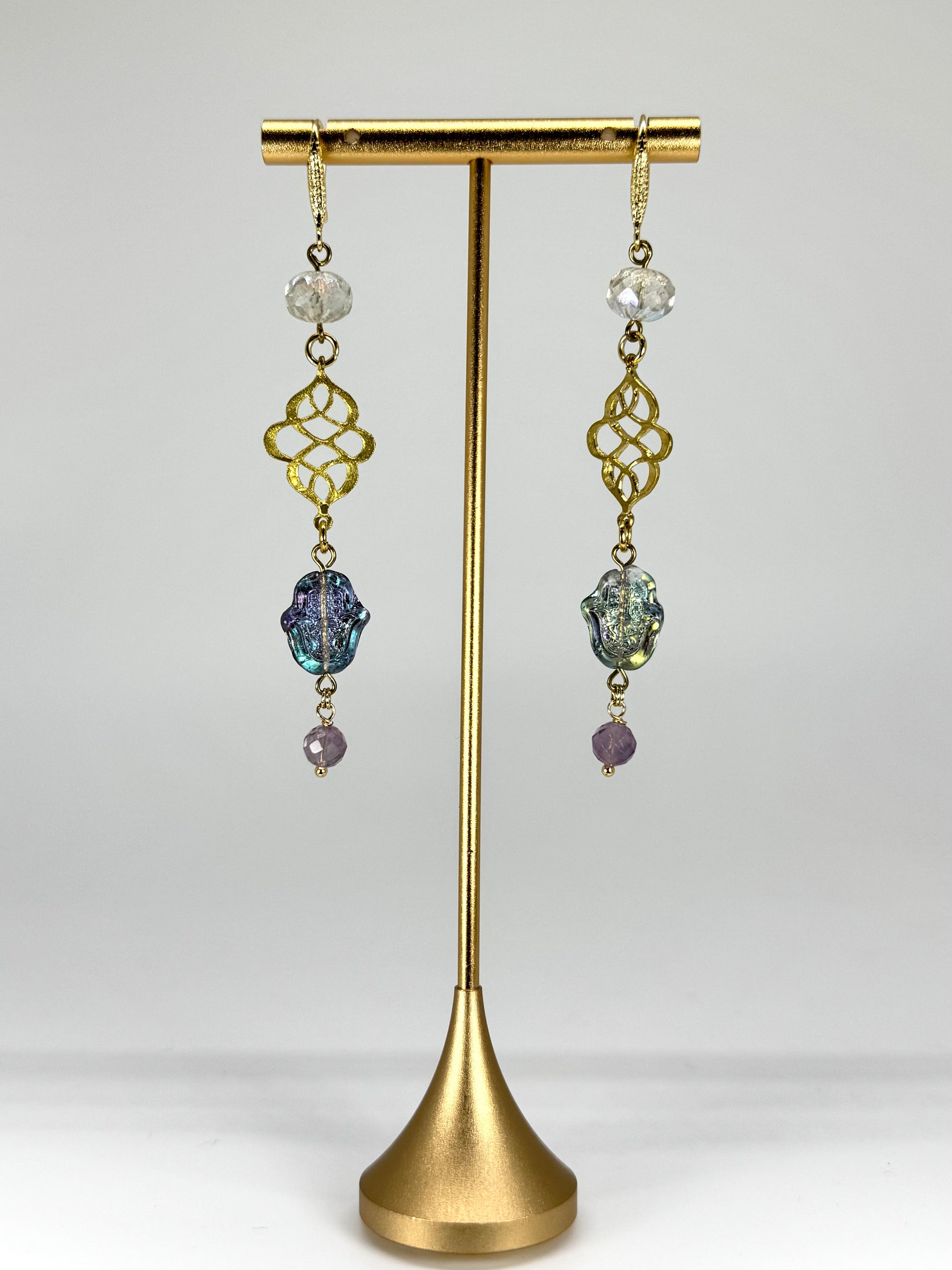 Pair of earrings on a gold stand against a white background