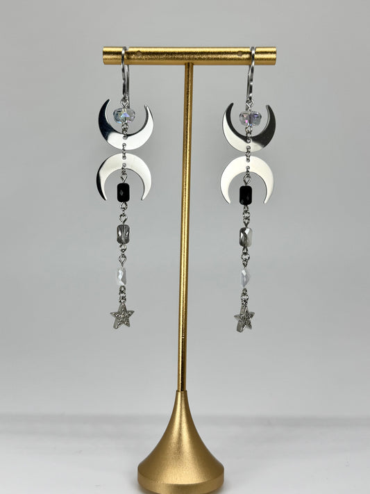 Pair of earrings on a gold stand against a gray background