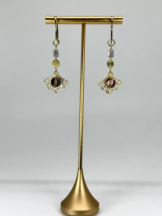 Pair of earrings on a gold stand against a gray background