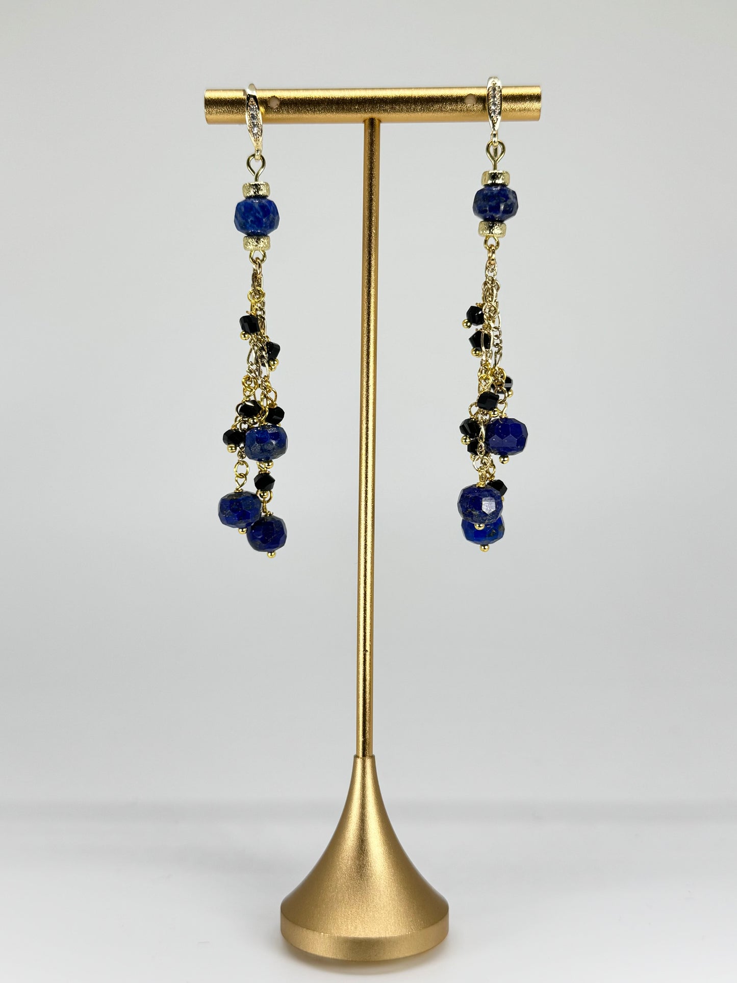 Pair of earrings with blue beads on a gold stand against a white background