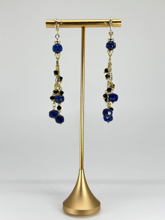 Pair of earrings with blue beads on a gold stand against a white background