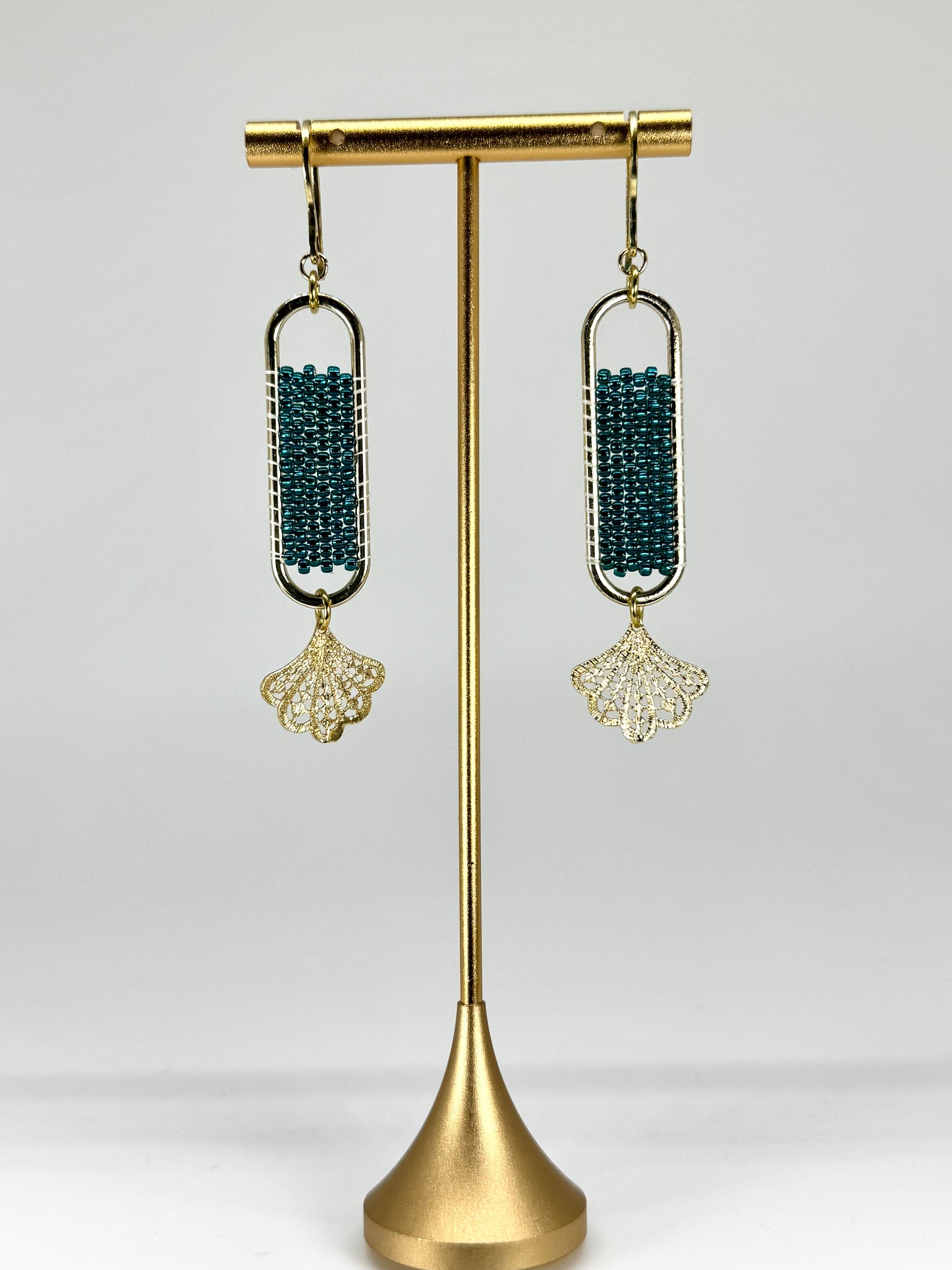 Pair of earrings on a gold stand against a white background