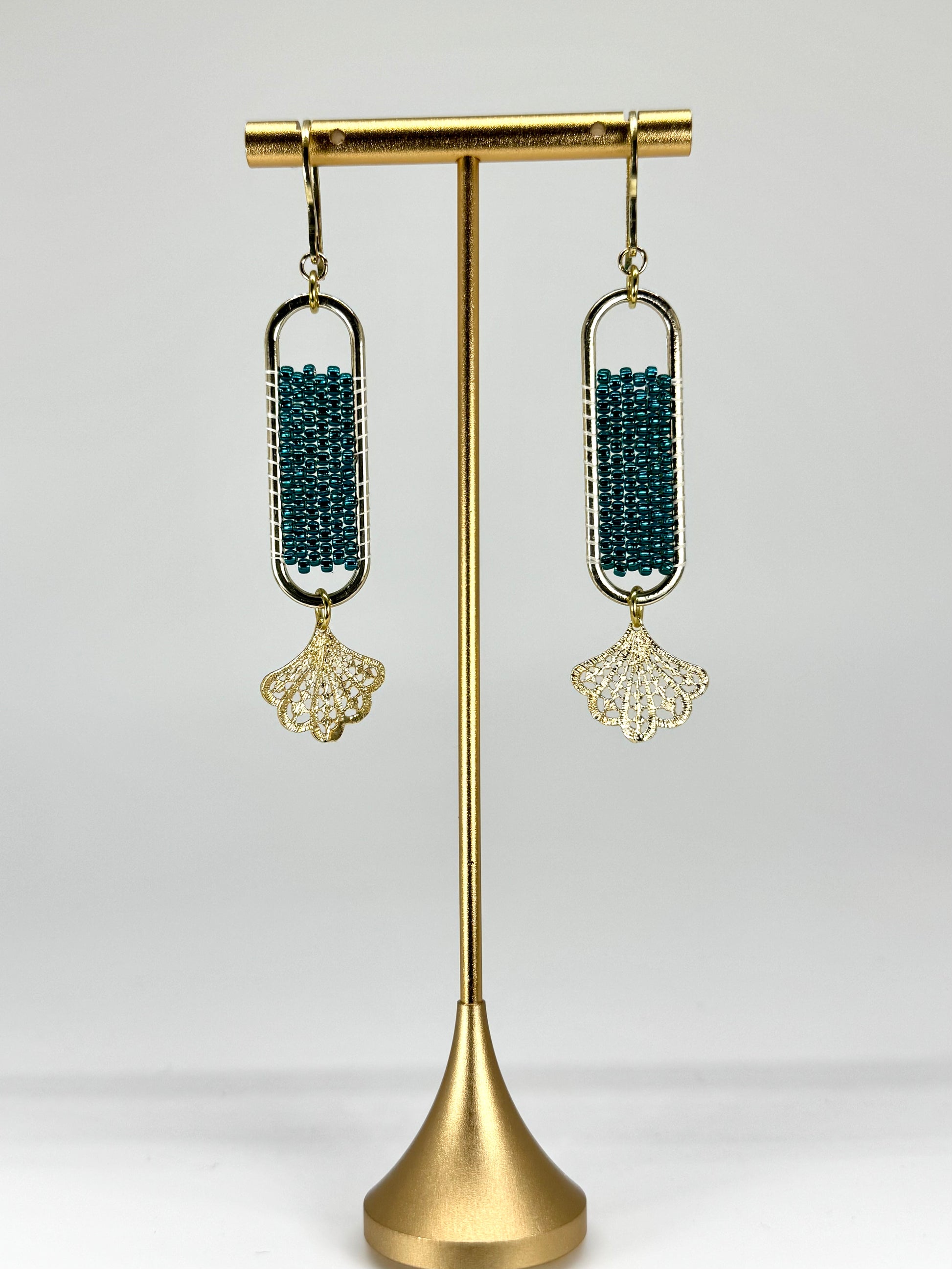 Pair of earrings on a gold stand against a white background
