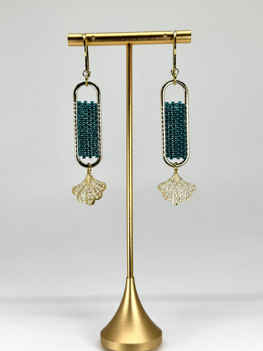 Pair of earrings on a gold stand against a white background