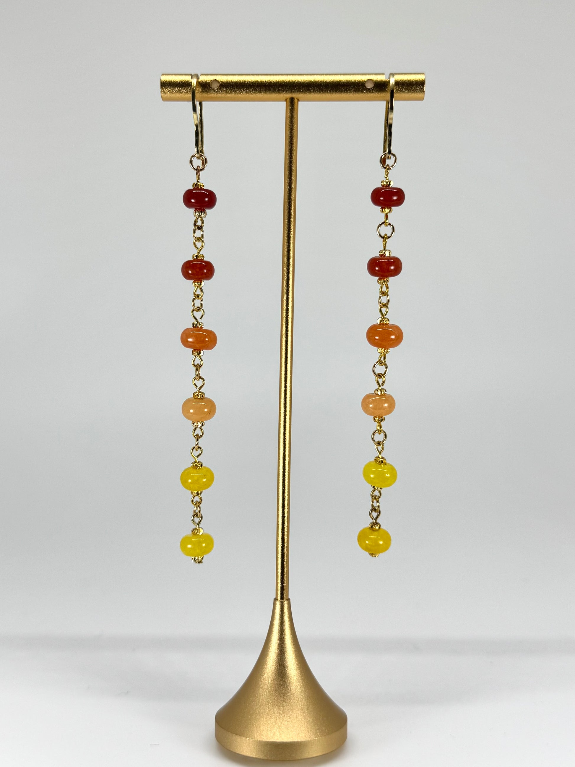 Pair of earrings with colorful beads on a gold stand against a white background