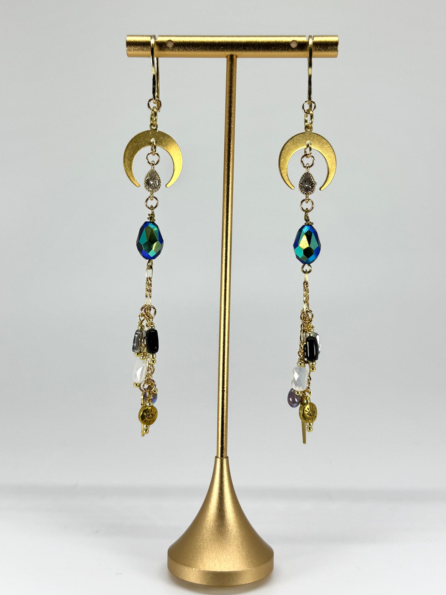 Gold earrings with colorful beads on a gold stand against a white background