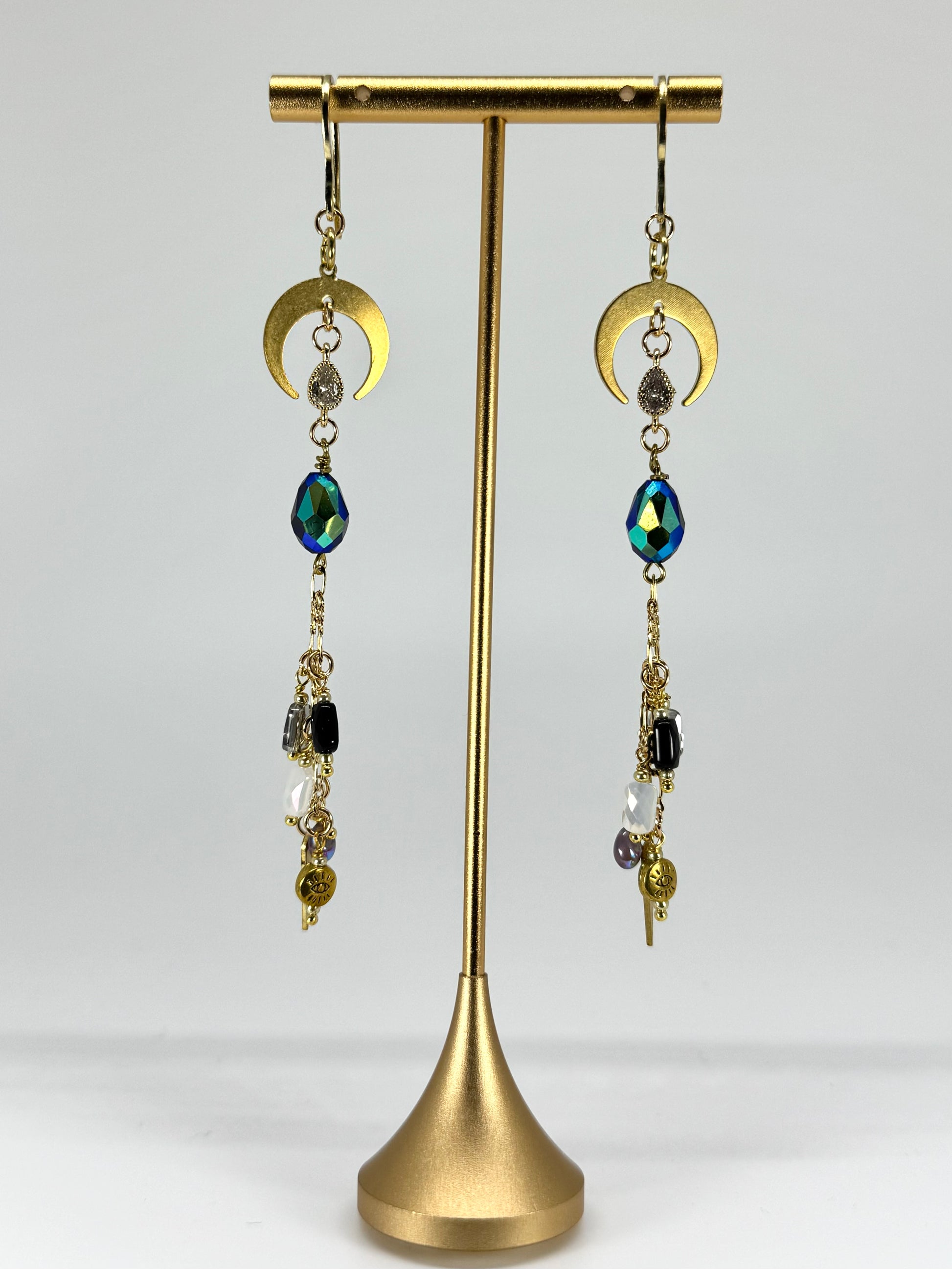 Gold earrings with colorful beads on a gold stand against a white background