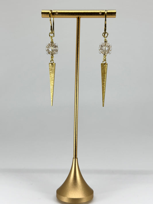 Gold earrings with cone-shaped designs on a gold stand against a gray background
