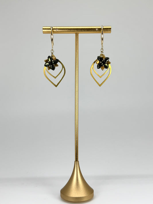 Gold earrings on a gold stand against a gray background