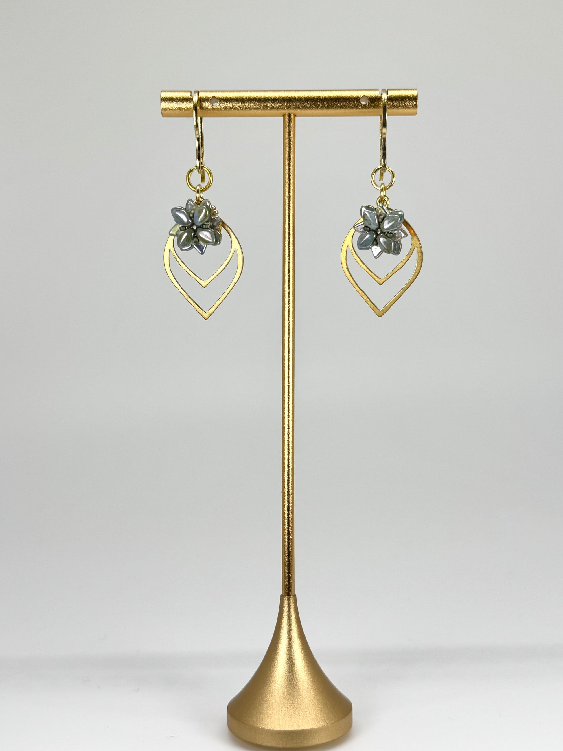 Gold earrings on a gold stand against a white background