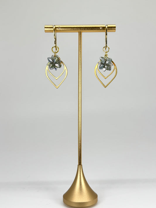 Gold earrings on a gold stand against a white background
