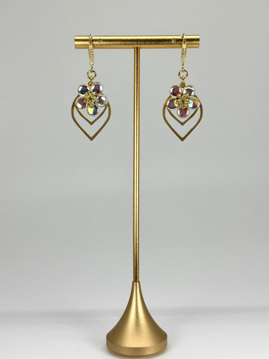 Gold earrings on a gold stand against a gray background