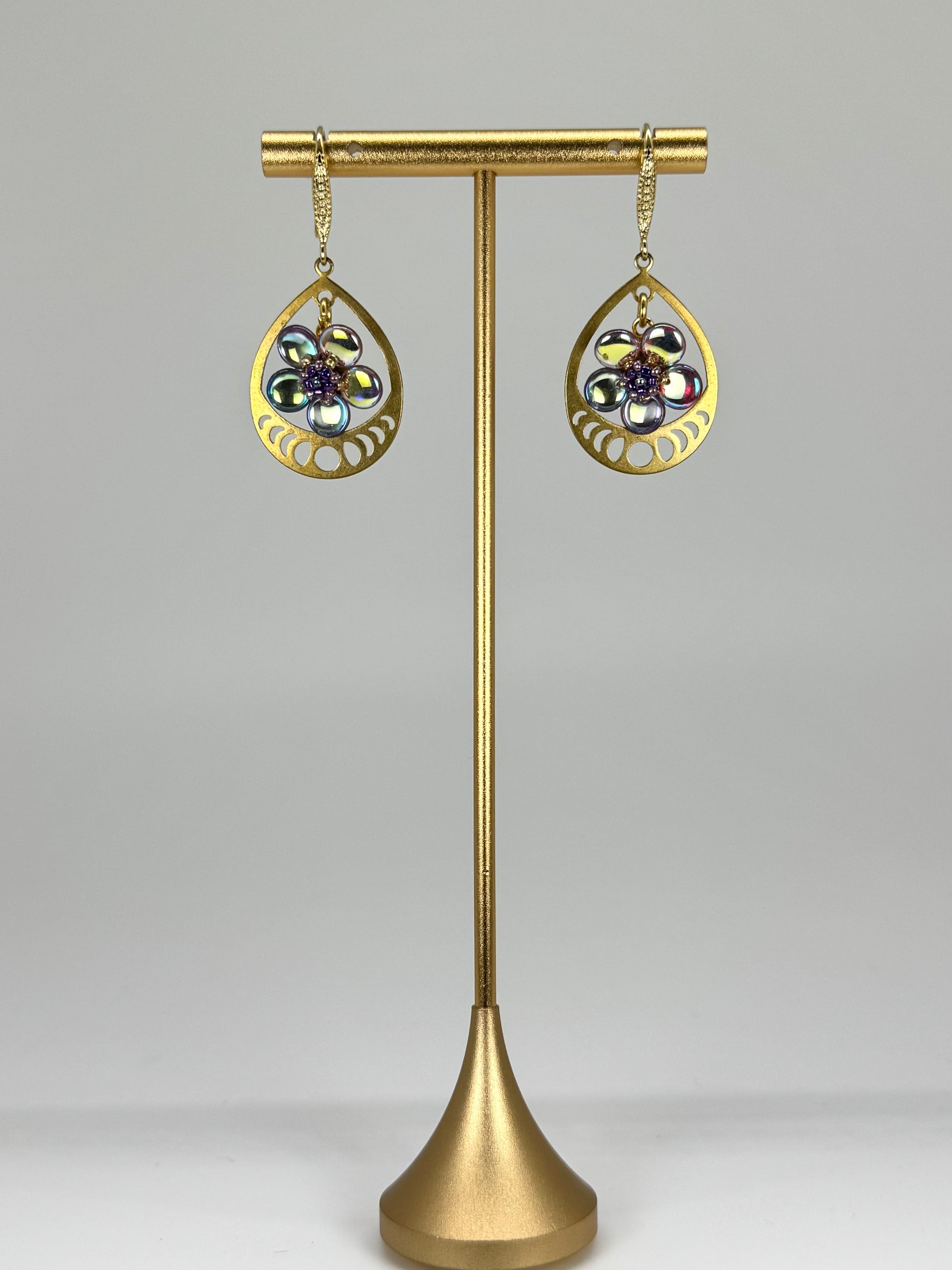 Gold earrings on a stand with a gray background