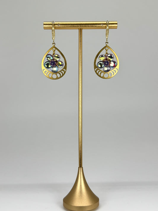 Gold earrings on a stand with a gray background