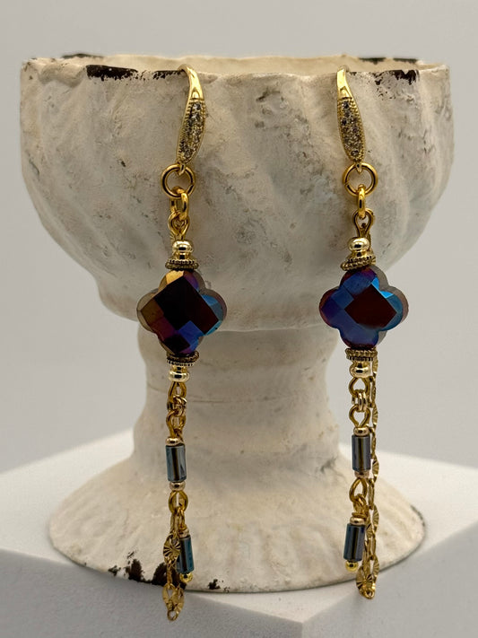 Pair of gold and blue beaded earrings on a textured stone stand.