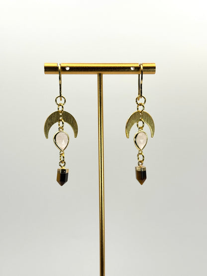 Gold earrings with moon-shaped hooks and gemstone drops on a white background