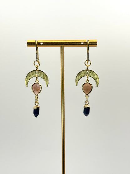 Pair of gold earrings with moon designs and gemstone drops on a white background