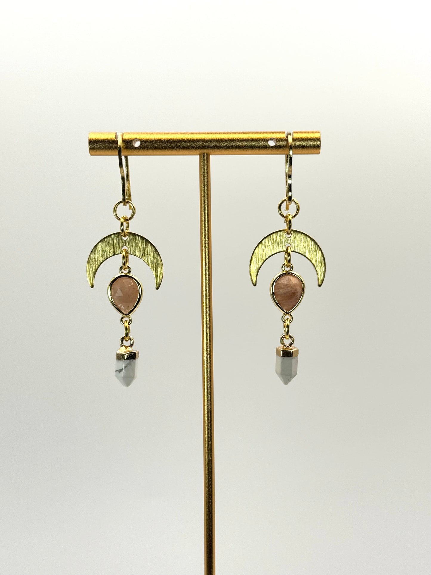 Gold earrings with moon designs and gemstones on a white background