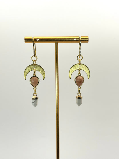 Gold earrings with moon designs and gemstones on a white background