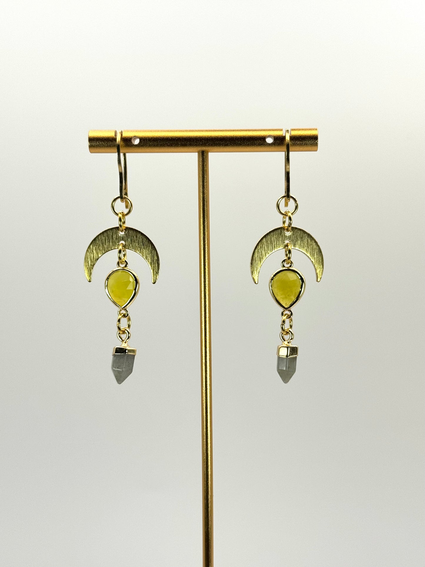 Gold earrings with green gemstones on a white background