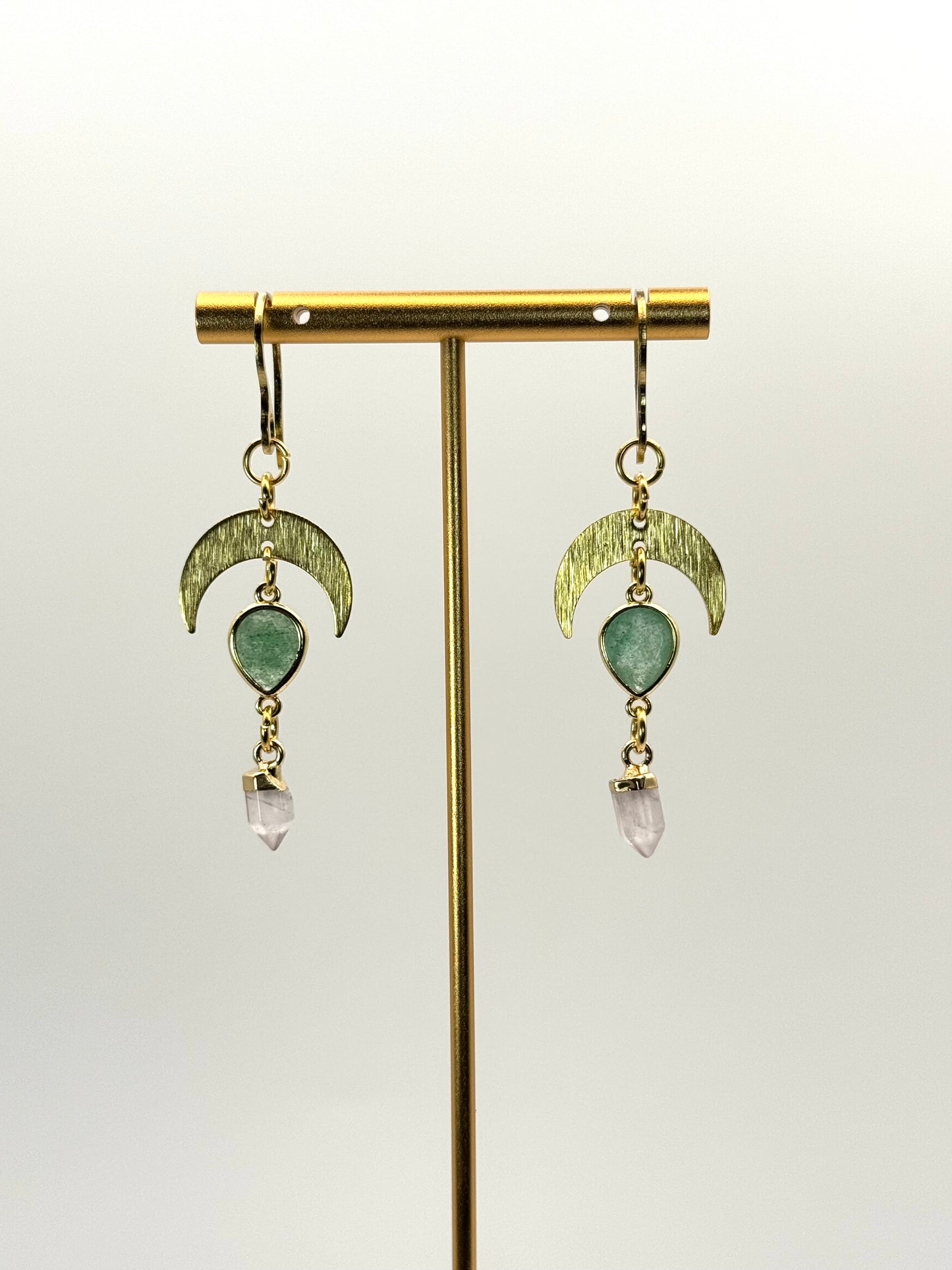 Gold earrings with green and pink gemstones on a white background