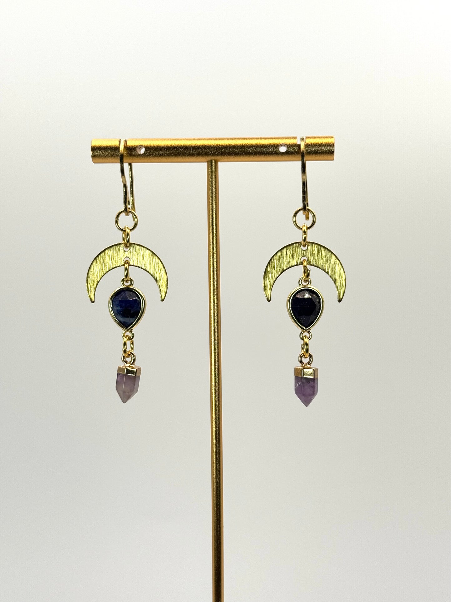 Gold earrings with moon designs and gemstones on a white background
