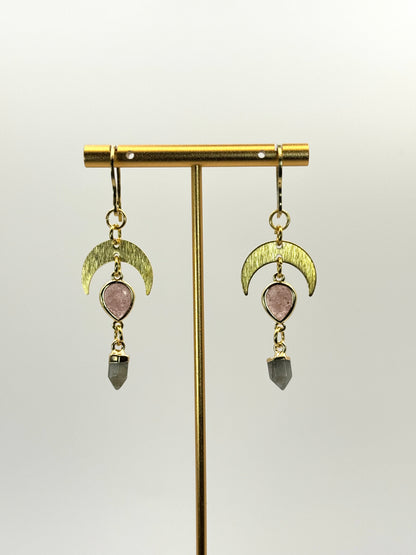Pair of earrings with gold crescent moon designs and gemstone drops on a stand.
