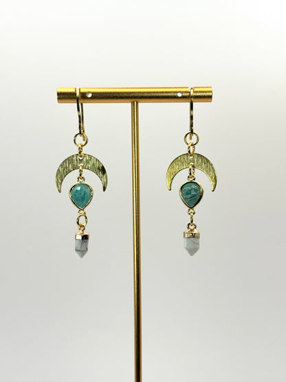 Pair of earrings with green gemstones and gold accents on a white background