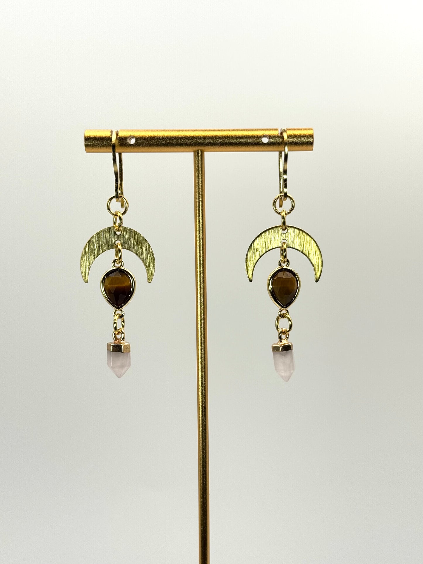 Gold earrings with moon designs and gemstones on a white background