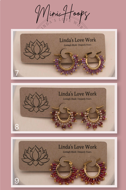 Three pairs of gold and purple hoop earrings on 'Linda's Love Work' cards against a pink background.
