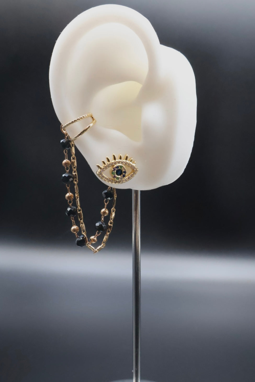 Earring displayed on a mannequin ear with a dark background