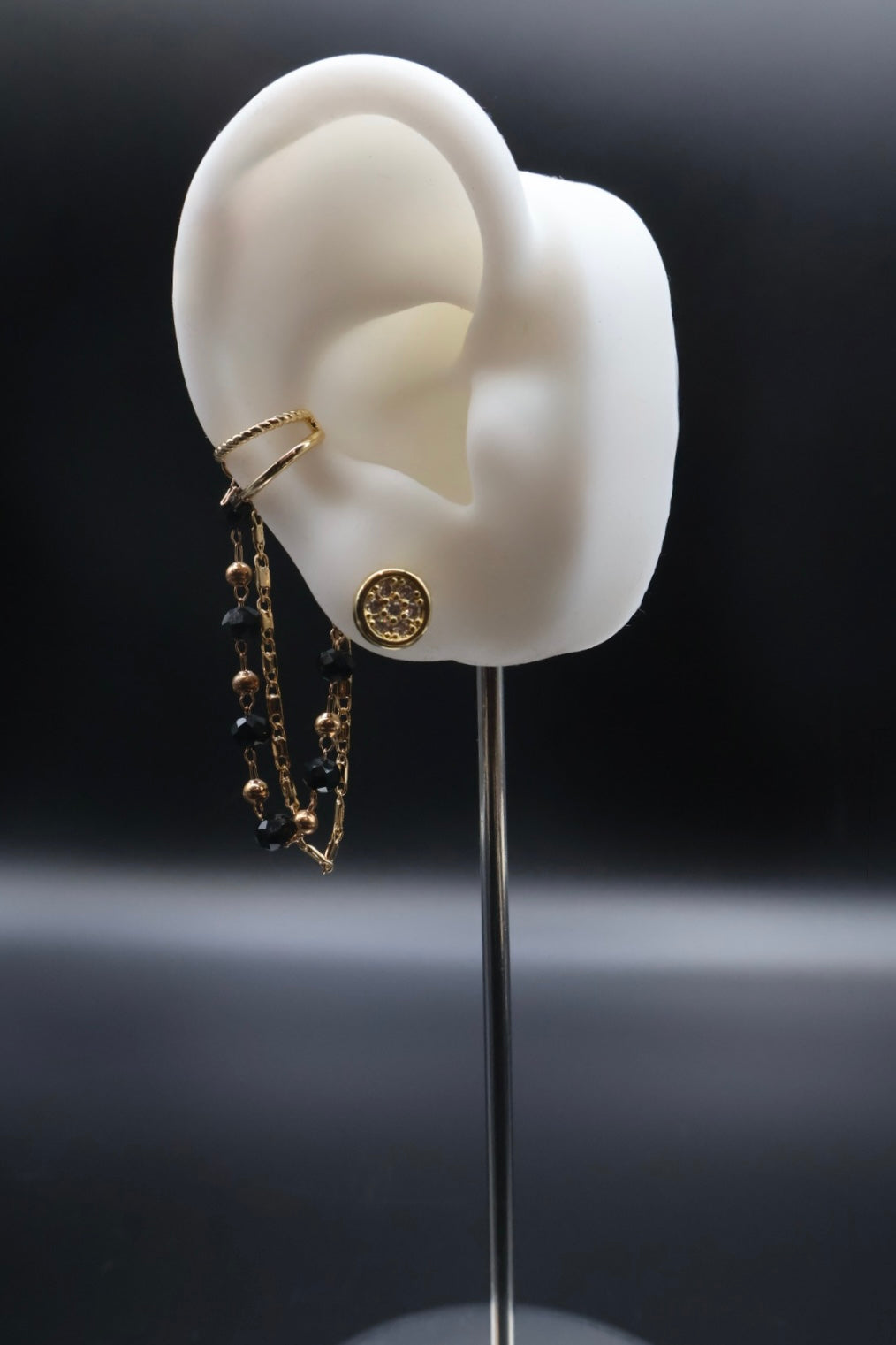Gold hoop earrings displayed on a white ear model against a dark background