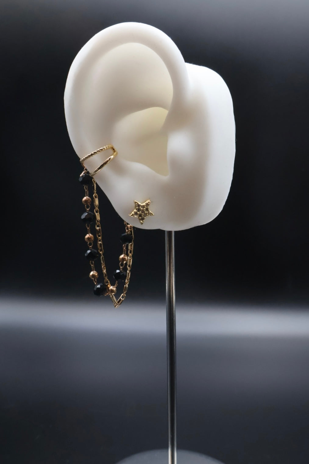Earring displayed on a white ear model with a dark background