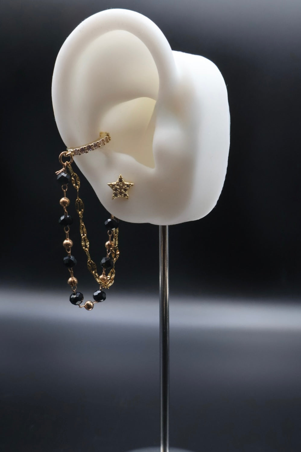 Earring displayed on a white ear model against a dark background