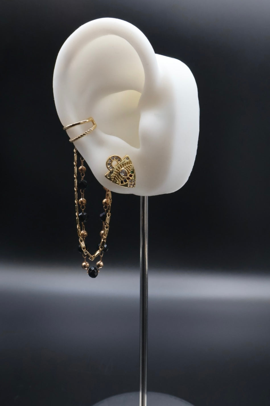 White ear model with gold earrings on a black background