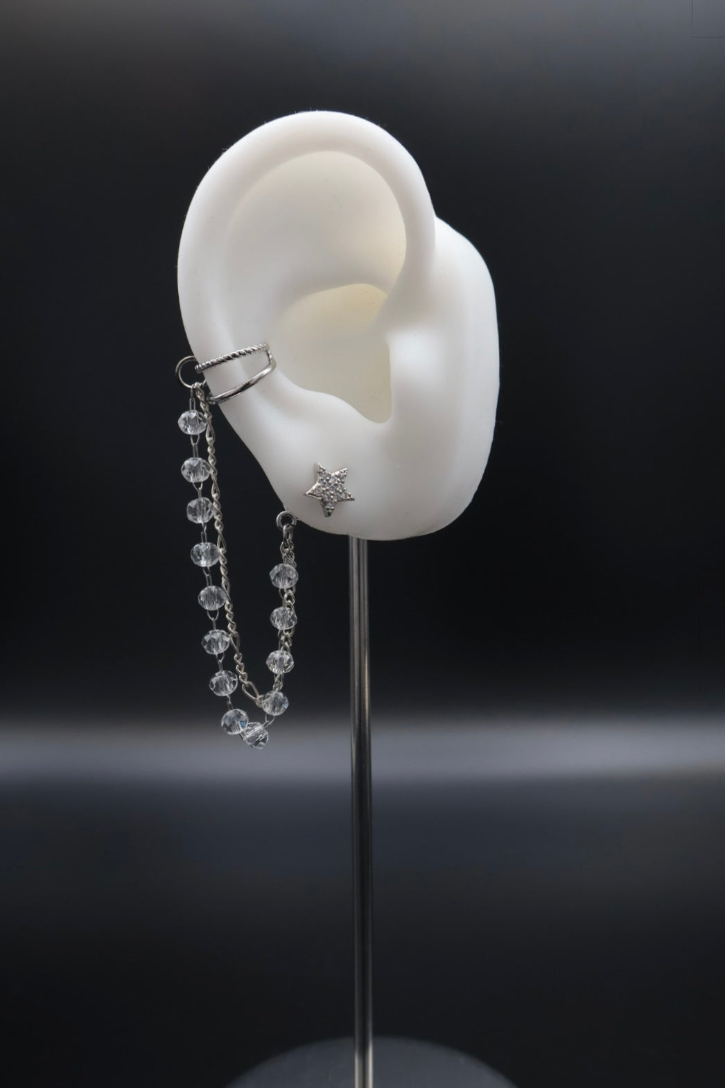 Dangle earring on a mannequin ear with a dark background