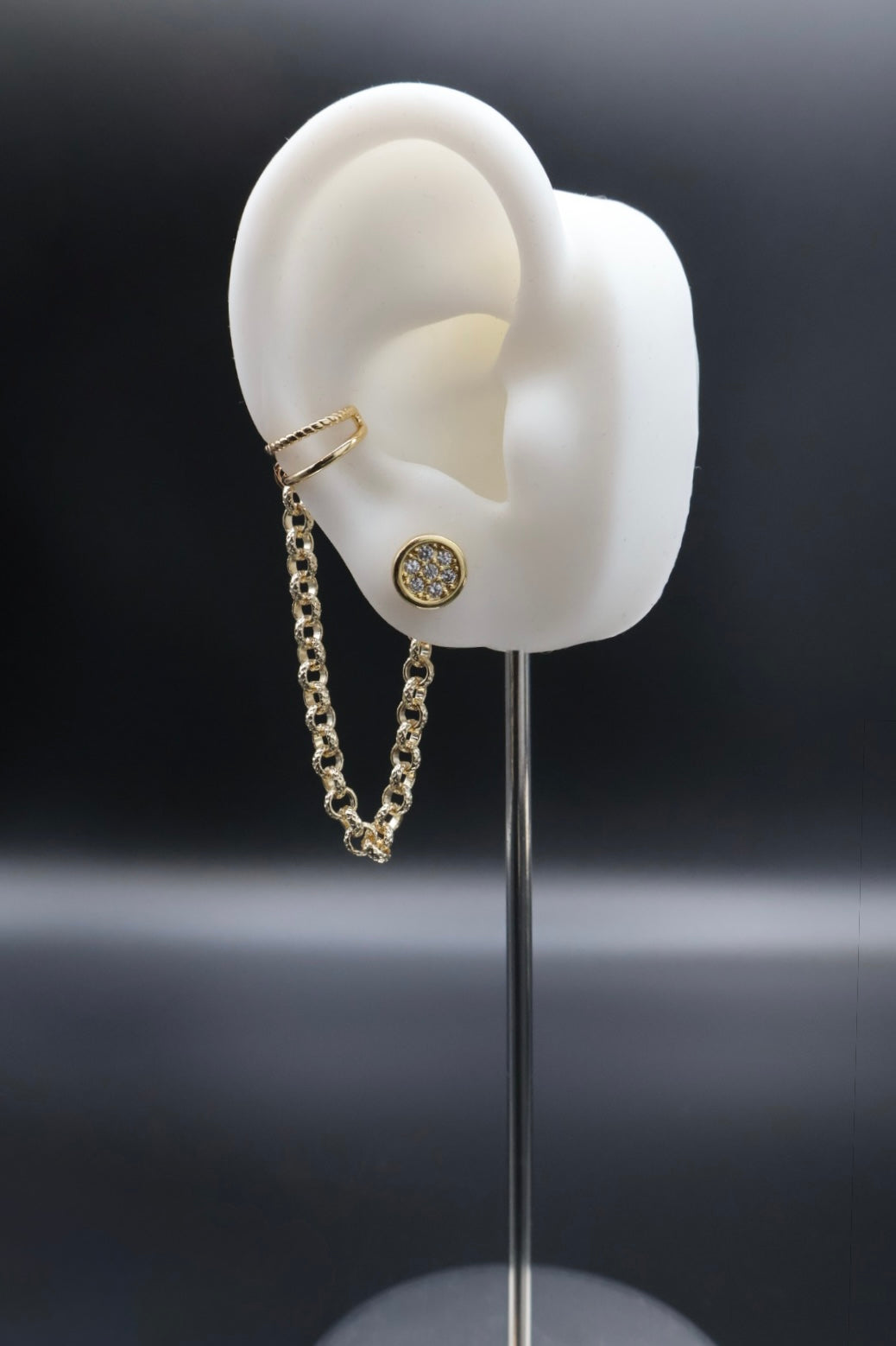 Gold earring on a stand with a black background