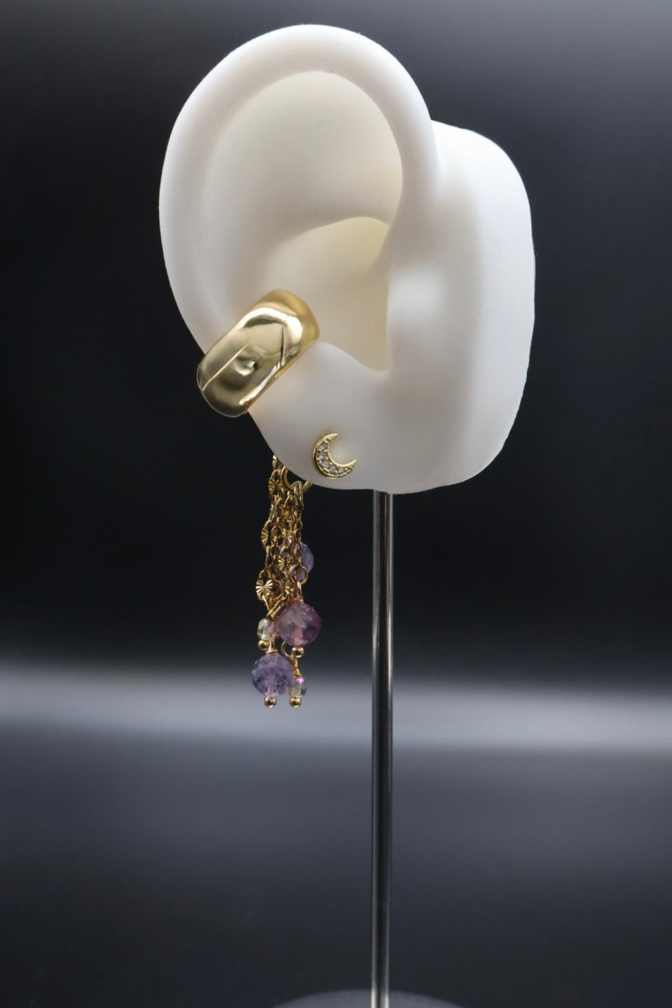 Gold earring with purple charms on a black background
