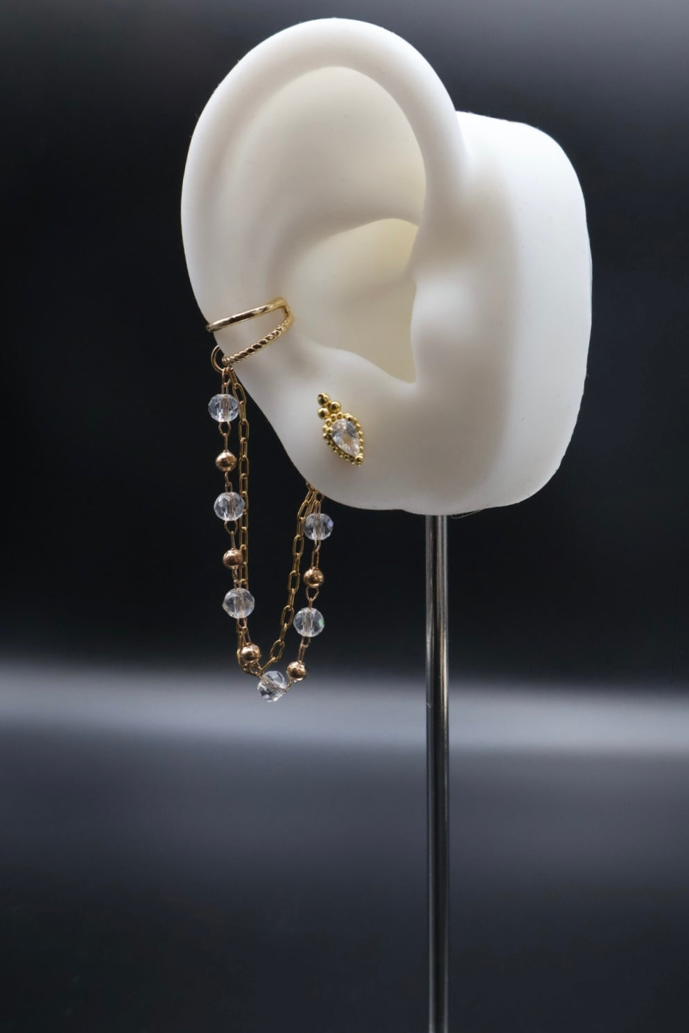 Earring displayed on a white ear model with a dark background