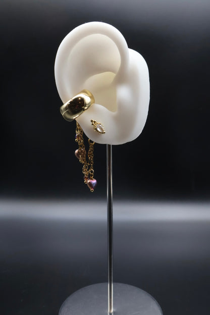 Gold earring with dangling charms on a black background
