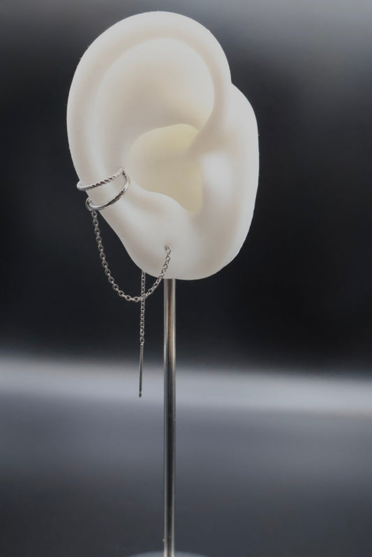 White ear model with a silver earring on a dark background