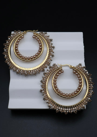 Pair of gold hoop earrings on a white rectangular platform with a black background