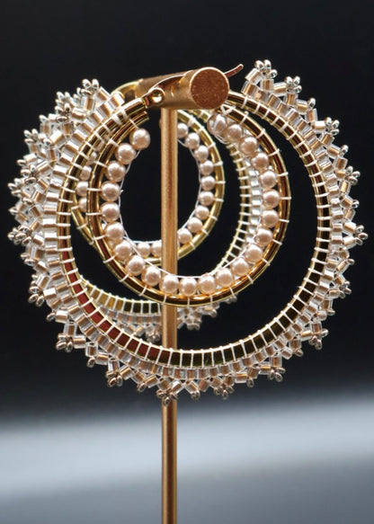Decorative brooch with circular design featuring pearls and gold elements on a black background
