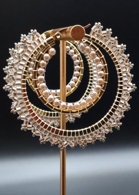 Decorative brooch with circular design featuring pearls and gold elements on a black background