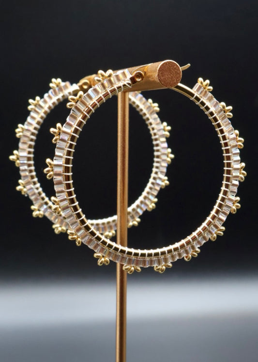 Gold hoop earrings on a stand against a dark background